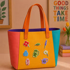 seven floral and ceramic vase embroidered patches on a bold color-block leather tote bag