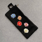 five cosmos flower embroidered patches in different colors on a black denim pencil case