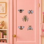 realistic insect specimen patches with black carpenter bee fluffy bumblebee slender wasp red-bellied bee and striped honey bee with translucent wings on a pink door