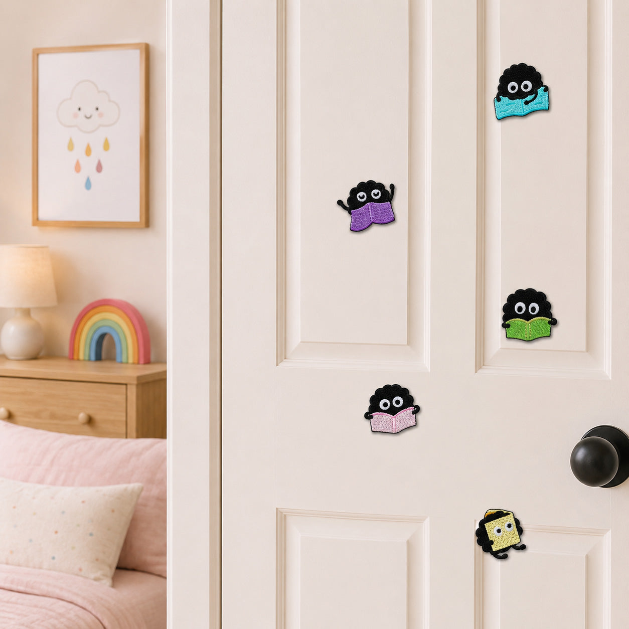 ghibli soot sprite reading purple blue green pink and yellow books stick-on patches displayed on a white bedroom door