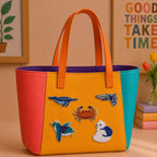 swordfish tropical fish crab kingfisher and polar bear stick-on patches decorating an orange and yellow color-block leather handbag
