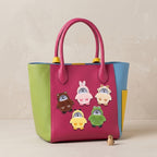 five chenille penguin patches in bear bunny sheep chick and frog costumes on a bold color-block leather bag