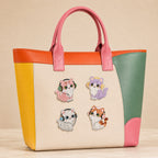 tabby persian and calico cats wearing colorful headphones stick-on patches decorating a pink and orange color-block leather handbag