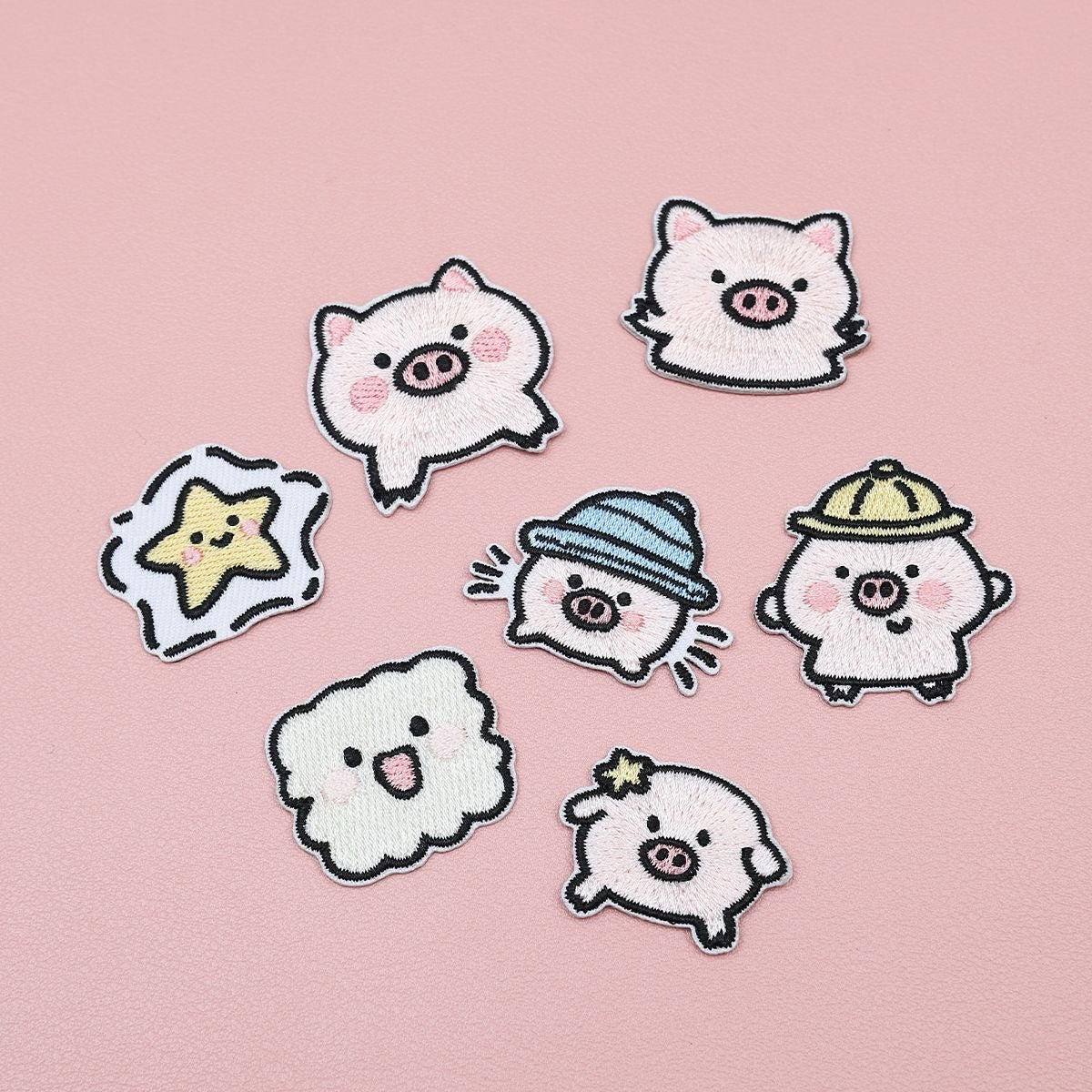 Seven embroidered stick-on patches featuring five pink piglets, a yellow star, and a smiling cloud
