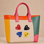 red black blue and yellow heart with eyes stick-on patches decorating a pink and orange color-block leather handbag