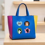 peeking cat portrait embroidered stick-on patches on a blue color-block leather tote bag