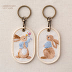 gathering wildflowers and looking up storybook bunny double-sided embroidered keychain charm poster
