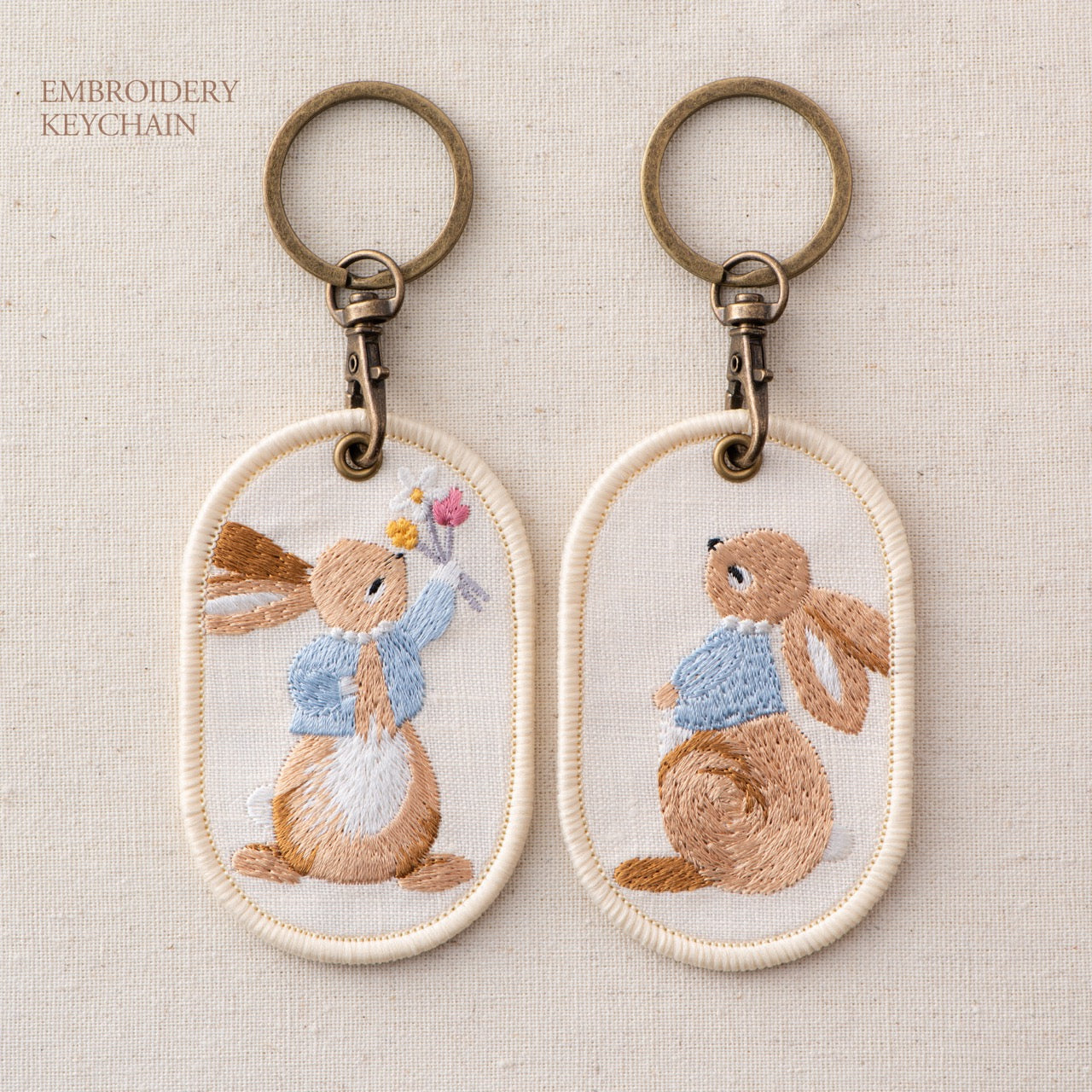 gathering wildflowers and looking up storybook bunny double-sided embroidered keychain charm poster