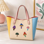cute polka dot mushroom stick-on patches in mixed colors decorating a yellow and blue color-block leather handbag