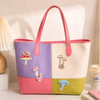 red spotted blue and pink wild mushroom stick-on patches decorating a purple and pink color-block leather handbag