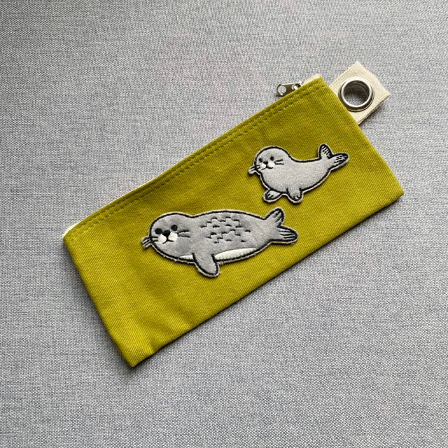 two harp seal embroidered patches on an olive canvas pencil case