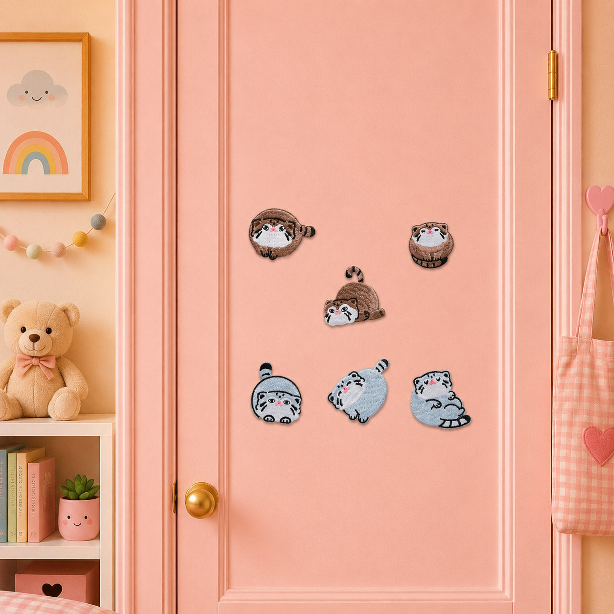 chubby round pallas cat with leopard markings and blue cat with pink blush in curled rolling and lying poses stick-on patches on a pink door in a pastel room