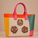 chinese dragon head with fire and peony embroidered stick-on patches decorating a pink and orange color-block leather handbag