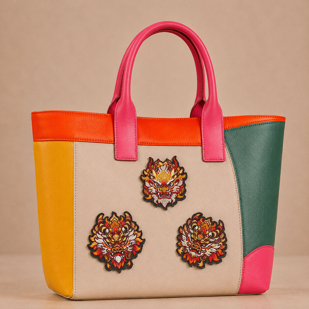 chinese dragon head with fire and peony embroidered stick-on patches decorating a pink and orange color-block leather handbag