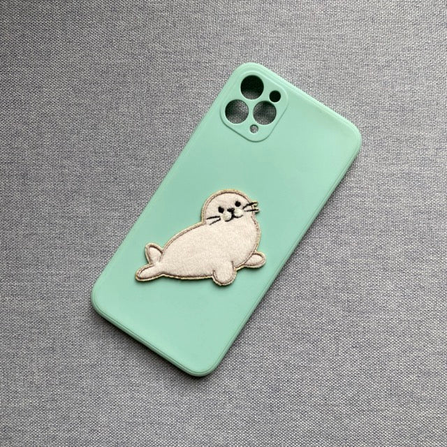fluffy harp seal embroidered patch on a mint green phone case