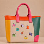 colorful alphabet letters with bunny bear and otter stick-on patches decorating a pink and orange color-block leather handbag