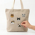 realistic cat breed embroidered patches being applied to a natural linen tote bag