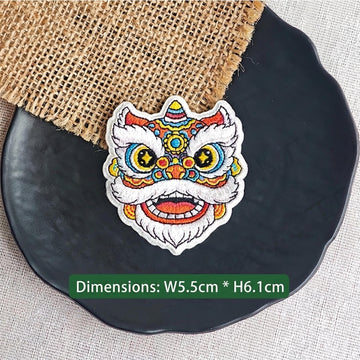red and gold Chinese lion dance embroidered stick-on patch — traditional warm red forehead with gold multicolor detail large yellow star-pupil eyes and white fur border open mouth