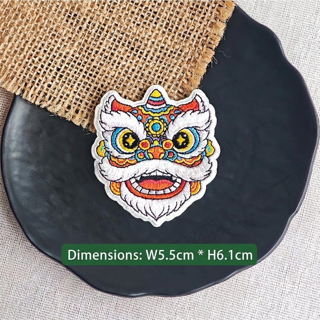 red and gold Chinese lion dance embroidered stick-on patch — traditional warm red forehead with gold multicolor detail large yellow star-pupil eyes and white fur border open mouth