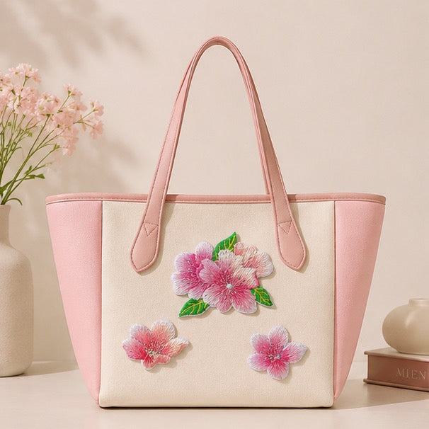 Cream tote with pink handles decorated with three pink cherry blossom embroidered patches
