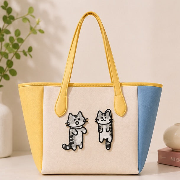 Funny cat embroidered stick-on patches decorating a tote bag with yellow handles
