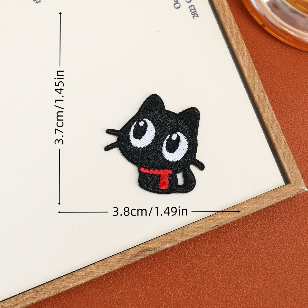 Sitting black cat embroidered stick-on patch with round white eyes and a red scarf
