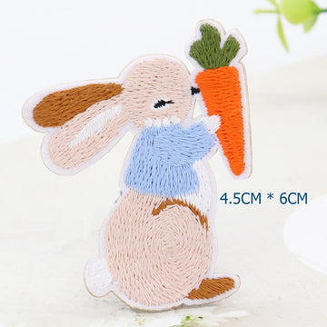 Bunny embroidered patch in a light-blue jacket holding a large orange carrot

