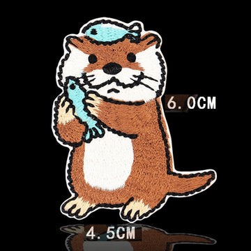 standing otter holding blue fish with fish on head embroidered stick-on patch