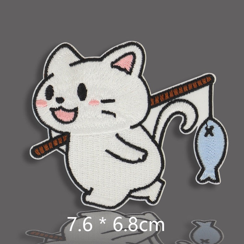 white cat holding fishing rod with small blue fish embroidered stick-on patch