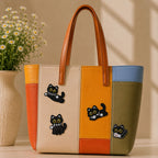 black cat with white striped scarf and daisy in jumping sitting crawling and lying poses stick-on patches decorating a bold orange yellow and olive stripe leather handbag