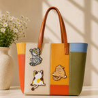 tabby cat pouncing calico cat rolling and orange cat back view stick-on patches decorating a bold orange yellow and olive stripe leather handbag