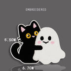 black cat hugging ghost embroidered stick-on patch — black cat with yellow eyes arms around white kawaii ghost with pink blush cheeks