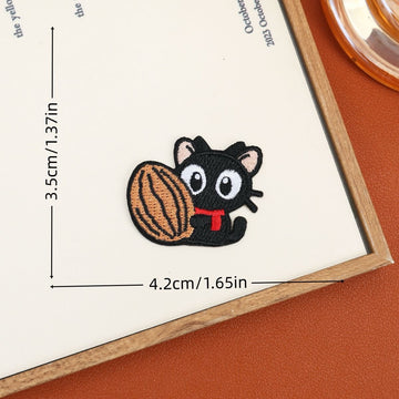Black cat embroidered stick-on patch hugging a large striped walnut
