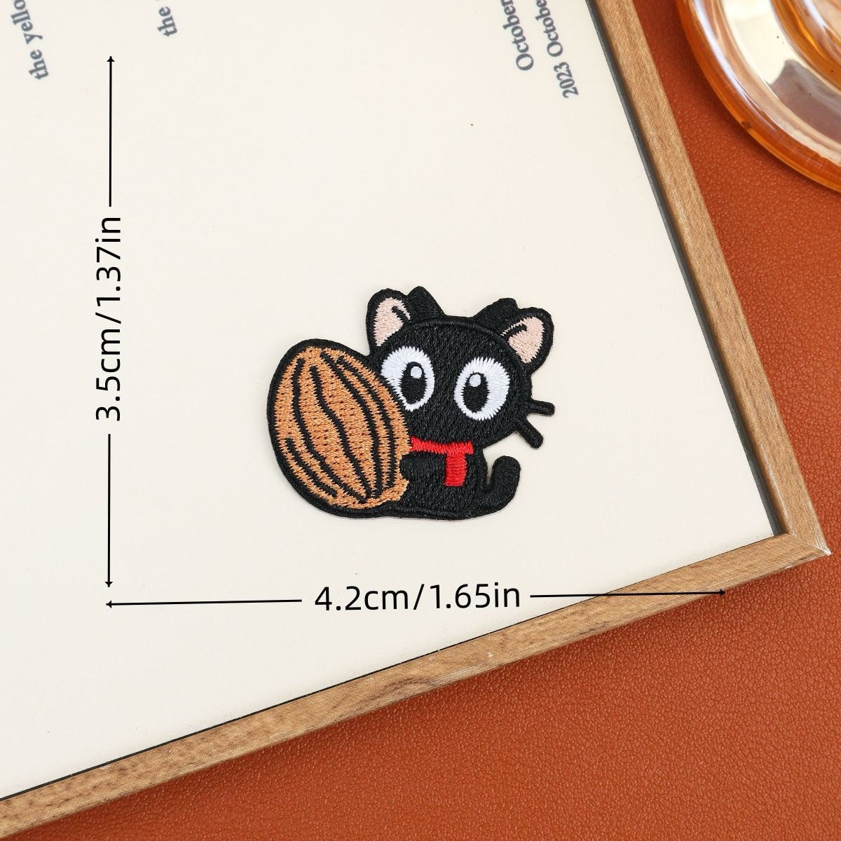 Black cat embroidered stick-on patch hugging a large striped walnut
