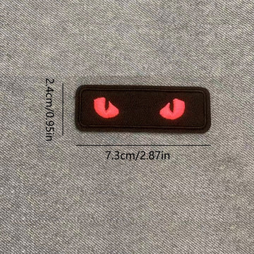 red glow-in-the-dark cat eye embroidered stick-on patch on black background
