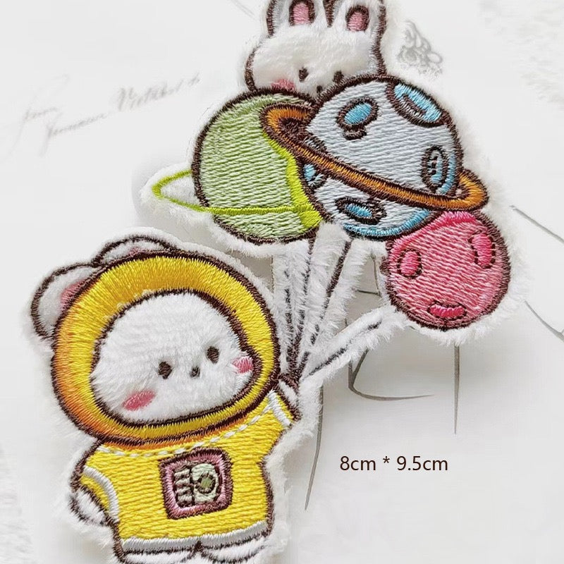 astronaut bunny with planet balloons embroidered stick-on patch — white bunny in yellow spacesuit holding string of colourful planet balloons