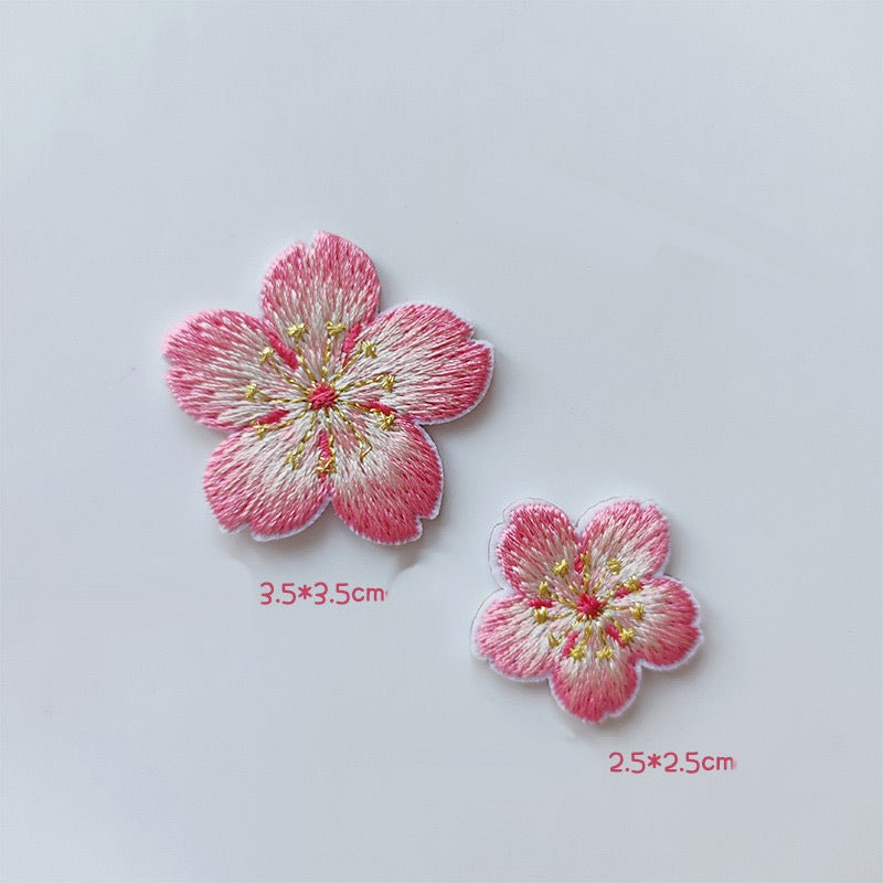Large and small cherry blossom patches with pink petal edges, creamy centers, and gold-tone stamens
