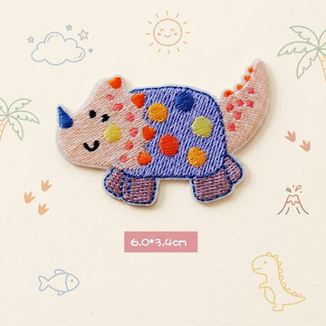blue spotted Triceratops kawaii embroidered stick-on patch — round wide blue purple triceratops covered in large multicolored polka dots with blue horn