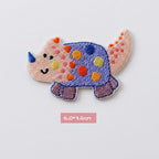 blue spotted Triceratops kawaii embroidered stick-on patch — round wide blue purple triceratops covered in large multicolored polka dots with blue horn