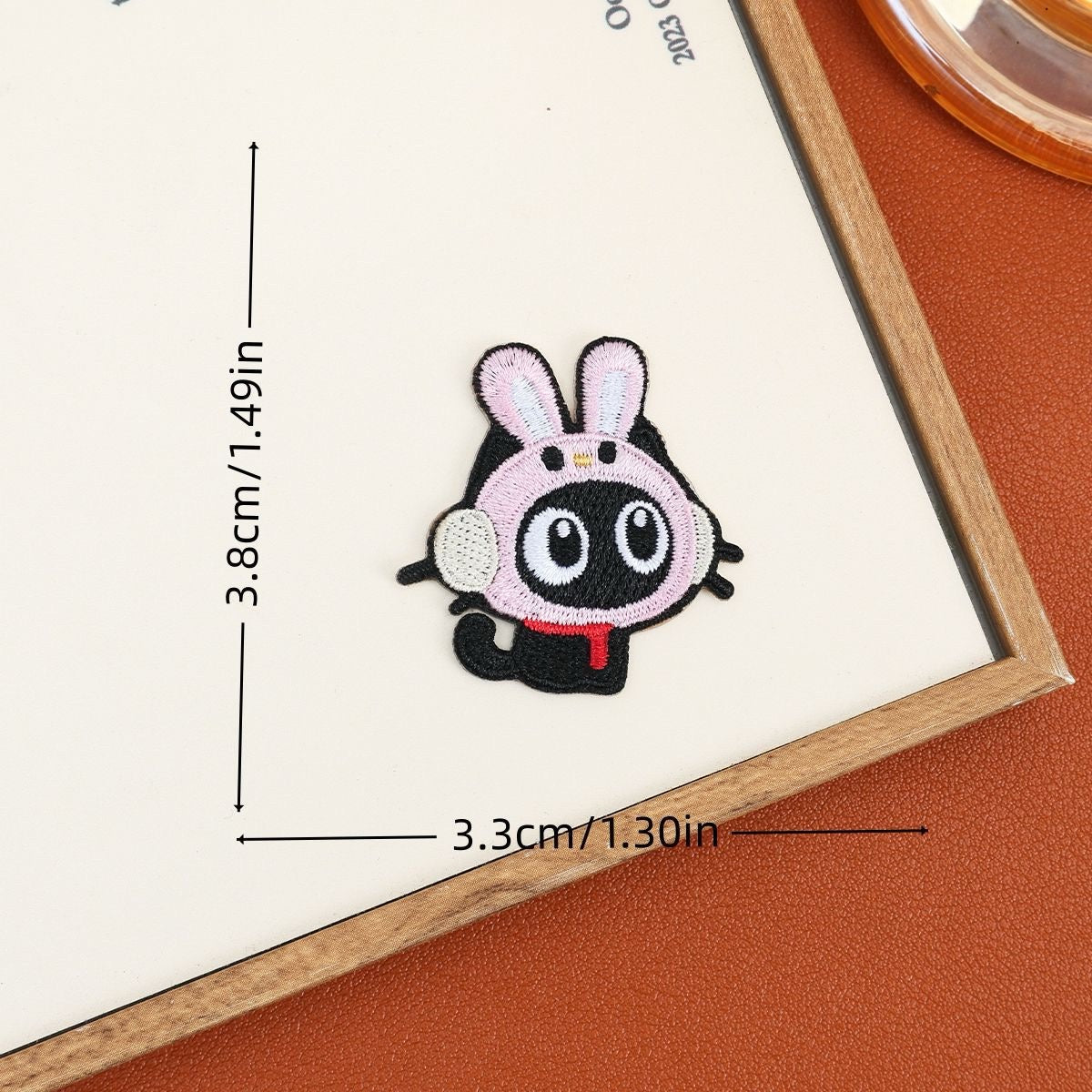 Black cat embroidered stick-on patch wearing a white bunny hood with pink-lined ears
