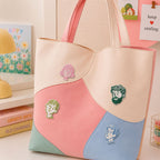 pink green teal and blue minimalist face portrait stick-on patches decorating a pink and cream wave color-block leather handbag