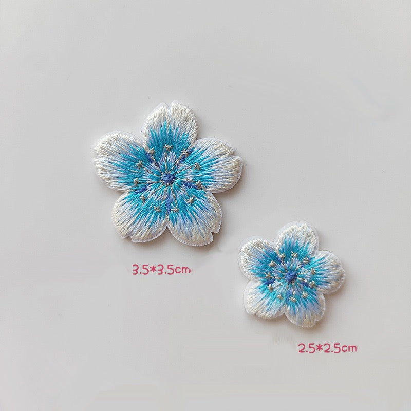 Matching cherry blossom patches with blue centers, white petal edges, and silver-tone stamens
