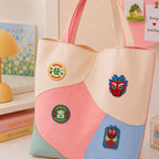 chinese fa ji lucky character badges and red dragon face stick-on patches decorating a pink and cream wave color-block leather handbag