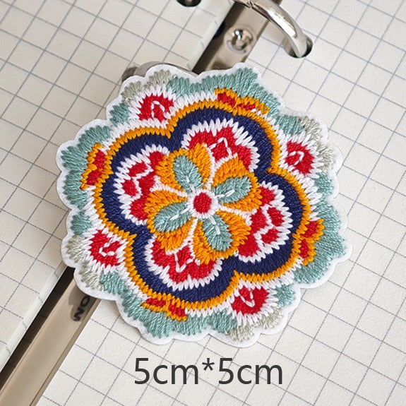 Four-lobed floral embroidered stick-on patch with navy-bordered petals

