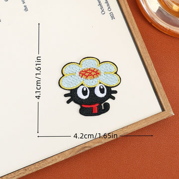 Black cat embroidered stick-on patch wearing a large pale flower with an orange center
