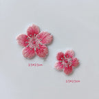 Large and small rose-pink cherry blossom patches with pale petal edges and silver-tone stamens
