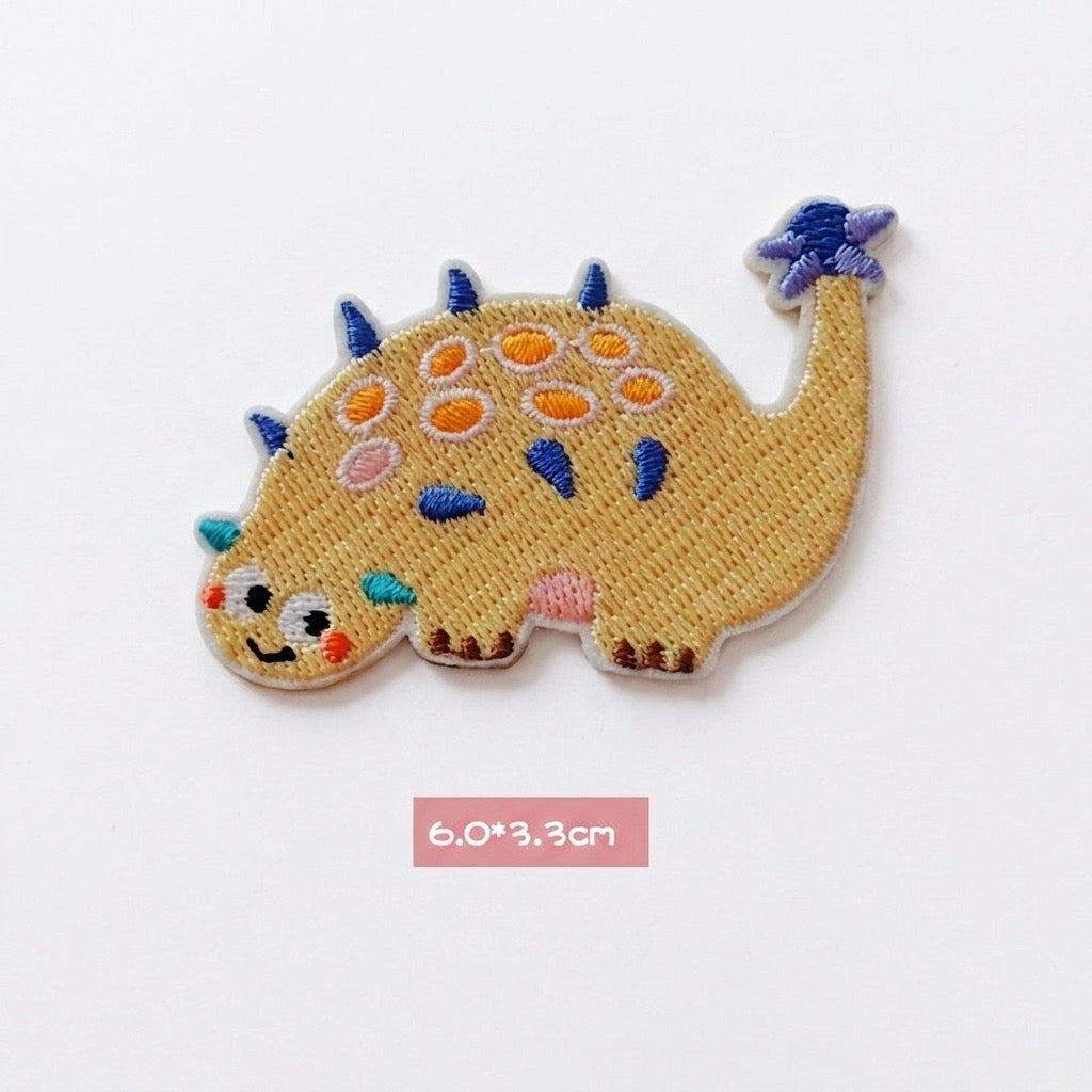 yellow Ankylosaurus kawaii embroidered stick-on patch — low wide yellow ankylosaur covered in round colorful armor plates tail curled upward