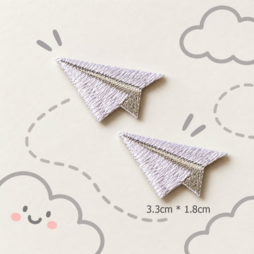 white paper airplane embroidered stick-on patches — pair of clean white satin embroidery paper planes with grey fold crease detail 33x18mm