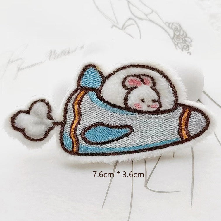 bunny in spaceship embroidered stick-on patch — white bunny lying in small blue flying saucer looking out from cockpit