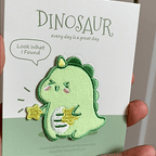 animated hand holding packaged cute dinosaur embroidered patches showing detailed embroidery texture